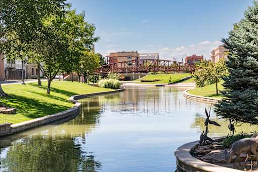 A statue of a bull is located on the right side of a pond.