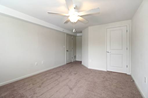 an empty living room with a ceiling fan and white walls