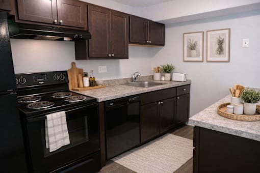 A kitchen with black appliances and brown cabinets.