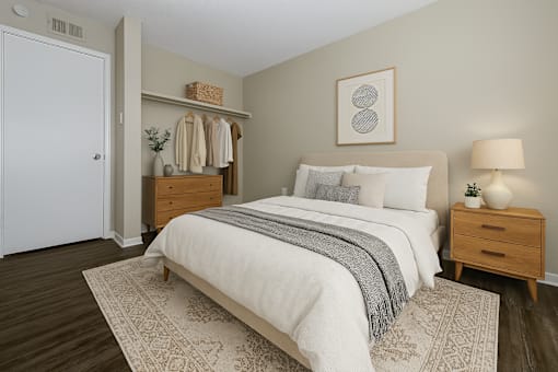 A bedroom with a large bed, a nightstand, and a dresser with clothes hanging on it.