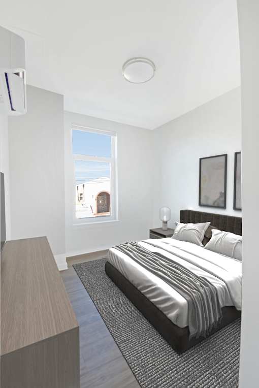 A bedroom with a large bed and a window overlooking a cityscape.