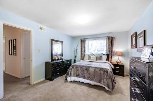 A bedroom with a bed, dresser, and mirror.