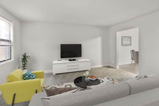 A living room with a grey sofa, a yellow chair, a white entertainment center, and a plant.