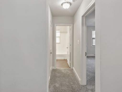 A long hallway with a carpeted floor and white walls.
