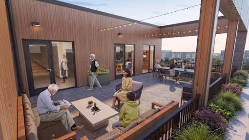 A group of people are sitting on a wooden deck with a table in the middle.