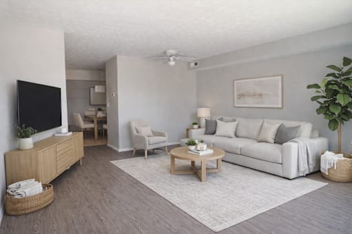 A living room with a white couch, a wooden coffee table, and a flat-screen TV.