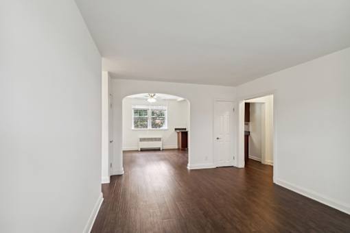an empty living room with white walls and wood floors