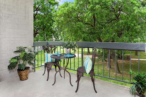 A patio with a table and chairs overlooking a green area.