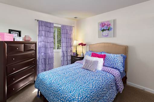 A bedroom with a blue patterned bedspread and matching curtains.
