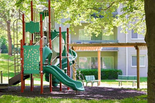 A playground with a green slide and a red structure.