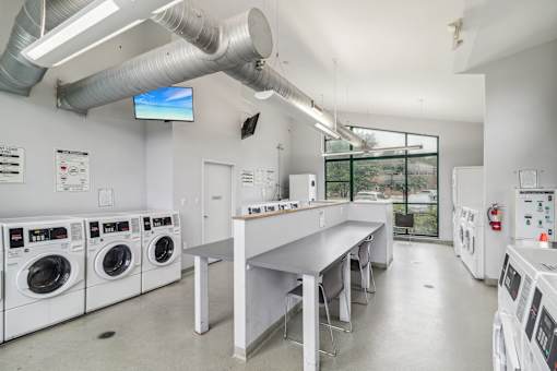 a laundry room with washers and dryers and a long counter with a sink