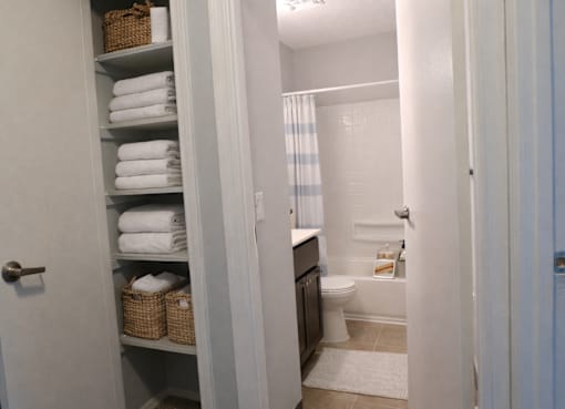 A bathroom with a toilet, a shower curtain, and a basket on the shelf.