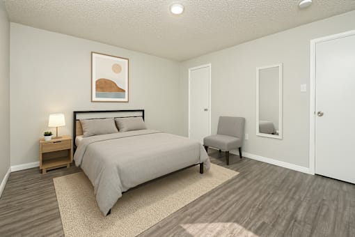 A bedroom with a bed, chair, and painting on the wall.