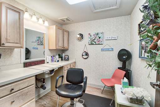 A room with a desk, chair, and a fridge.