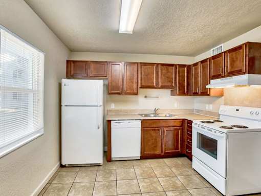 A kitchen with white appliances and brown cabinets.