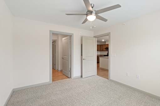 A room with a ceiling fan and carpeted floor.