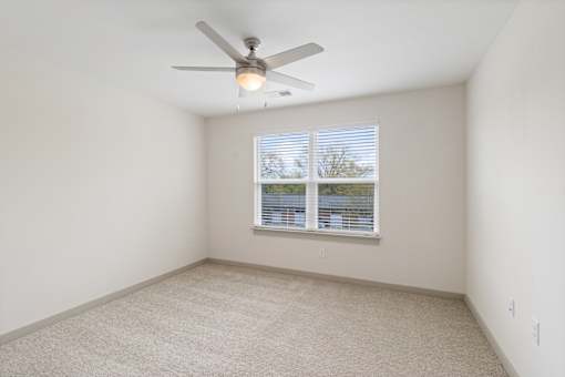A room with a ceiling fan and a window with blinds.