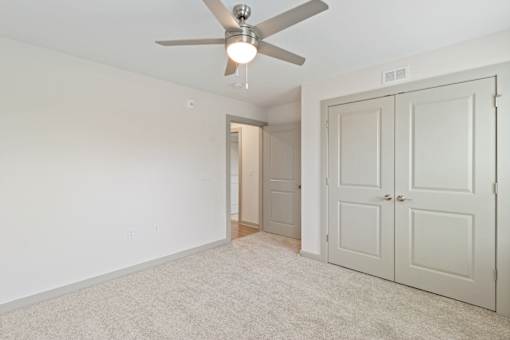 A room with a ceiling fan and carpeted floor.
