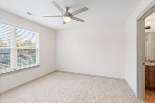 A room with a ceiling fan and a window with blinds.