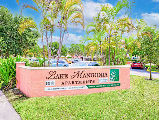 A sign for Lake Mangonia Apartments is displayed in front of some trees.
