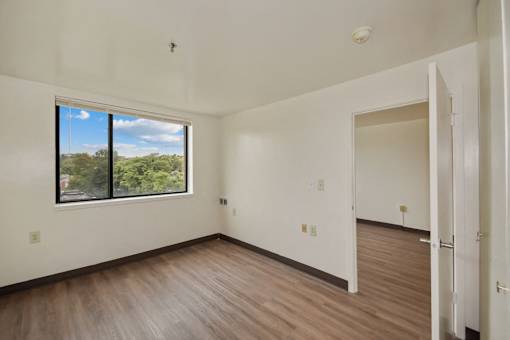 an empty living room with wood floors and a large window