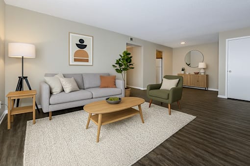 A living room with a grey couch, a green armchair, a wooden coffee table, and a lamp.