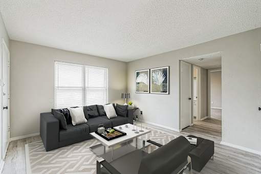 A living room with a grey couch, a coffee table, and a painting on the wall.