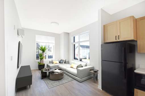 A modern kitchen with a black refrigerator and wooden cabinets.