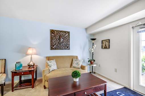 A living room with a brown couch, a wooden table, and a lamp.