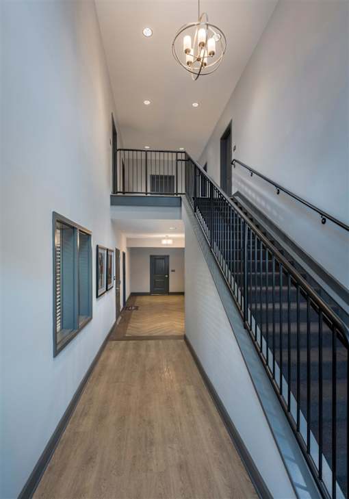 a long hallway with a staircase and a light hanging from the ceiling