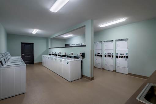 the laundry room is equipped with washers and dryers and a row of sinks