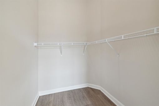 an empty closet with white walls and a wood floor