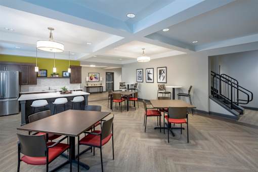 a dining room with tables and chairs and a kitchen with a staircase