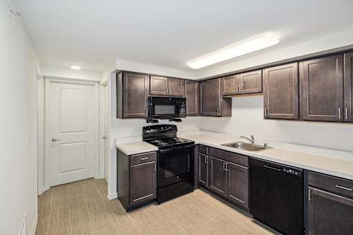 a kitchen with dark wood cabinets and black appliances