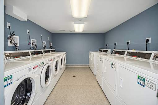 a laundry room with many washers and dryers and a row of washing machines