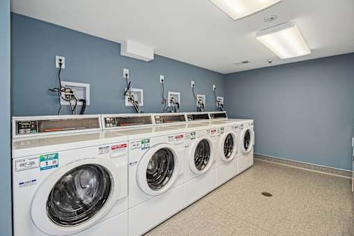 a washer and dryer in a laundry room with a row of washing machines