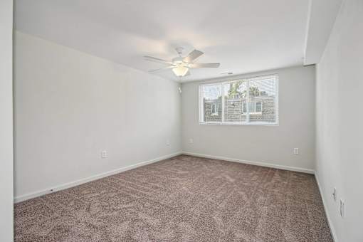 an empty living room with a ceiling fan and a window