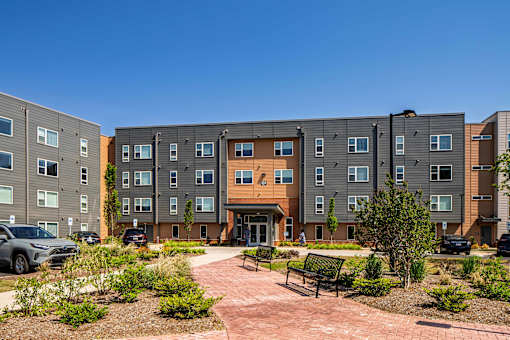 A modern apartment complex with a courtyard and parked cars.