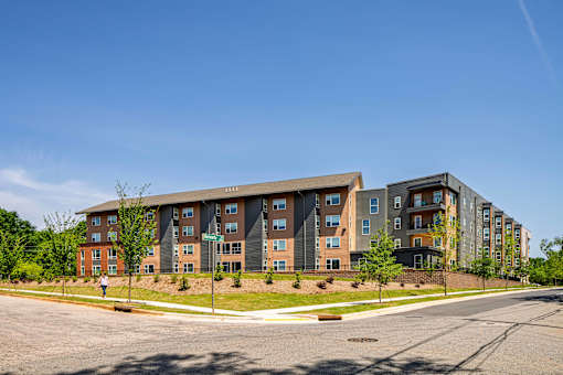 A large apartment complex with multiple buildings and a person walking in front.