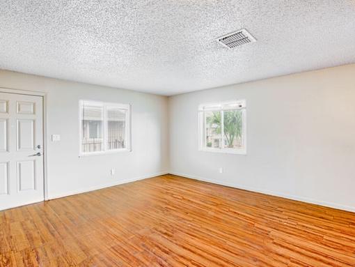 A room with wooden floors and two windows.