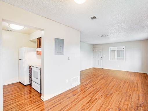 A kitchen with white appliances and wood floors.
