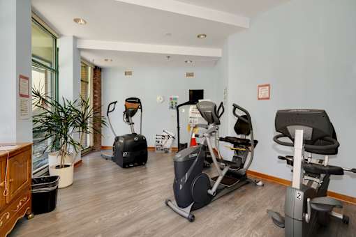 a gym with various exercise machines on the floor and a window