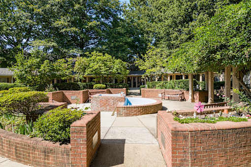 a courtyard with a pool and benches and trees
