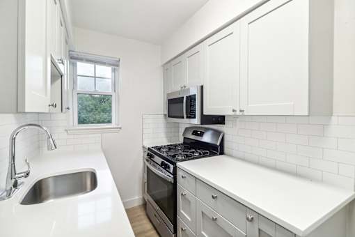 a kitchen with white cabinets and black appliances and a sink
