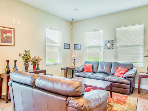 A living room with a brown leather couch and a grey one.