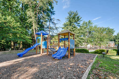 A playground with a blue slide and a wooden structure.
