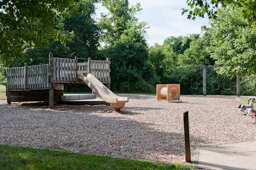 a playground with a wooden playset and some trees