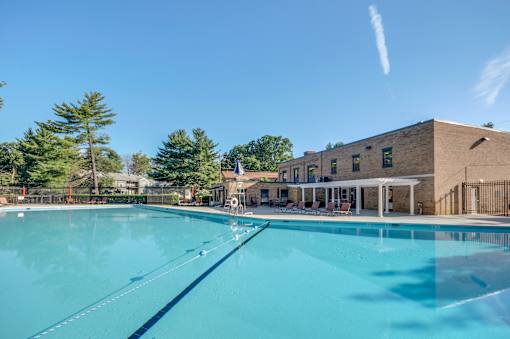A large swimming pool in front of a building with trees in the background.