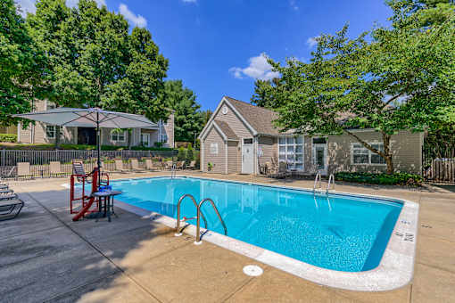 a swimming pool with chairs and a house in the background
