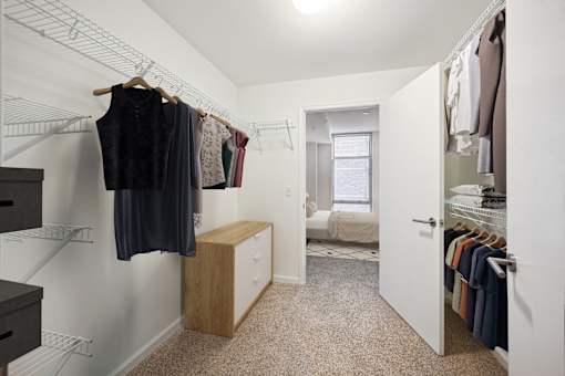 a walk in closet with clothes hanging on a rack and a door to a bedroom